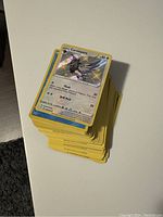 Stack of Pokémon cards featuring a holographic Corvisquire card on top, showing the condition and quantity of cards.