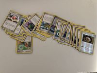 A spread of about 40 yellow-border Pokemon Trainer cards showing various Trainer items and effects such as Energy Removal and PlusPower.