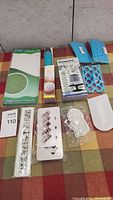 Full lot showing multiple fondant impression tools including boxed mats, rollers, decorative molds, and smoothers laid out on plaid cloth.