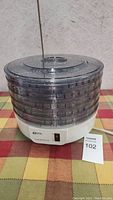 Full view of K-Tel food dehydrator with stackable transparent trays and white base.