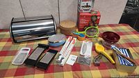 Kitchen essentials including bread box, graters, measuring spoons, lemon squeezer, spice grinder, trivets and more
