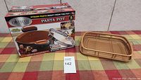 Photo showing Gotham Steel pasta pot with box and separate oven tray on table