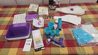 Lot contents arranged on table showing piping bags, icing tips, silicone molds, decorating brushes, plastic cups, and decorating tools