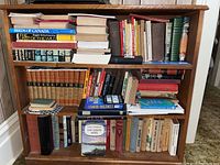 Photo of bookshelf with assorted hardcover and softcover books in various conditions and genres, some vintage.