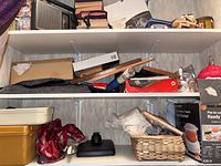 Three shelves with a mix of items including a radio, boxes, tins, books, sewing basket, and small household items.
