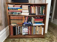 Front facing rectangular wooden bookshelf with three shelves filled with books, no contents included in sale.
