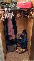 Closet showing coats hanging on hangers and bags on the floor