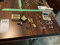 Wide view of largest part of lot showing various earrings, brooch and cufflinks arranged on table