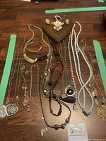 Overhead view of all items on a table showing necklaces, bracelets, rings, and wooden wall hanging keeper.