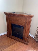 Front view of the wood corner electric fireplace showing the polished wooden finish and the electric log insert.
