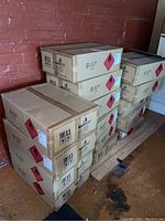 Stack of sealed cardboard boxes labeled as containing hand sanitizer, each box has hazard warning labels indicating flammable liquid.