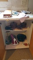 Photo of kitchen counter shelves showing Vision Ware pots, fry pan, letter organizer, kitchen linens, handheld vacuum, and various small items.
