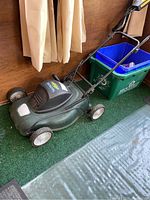 Full view of the green Yardworks electric compact lawn mower showing wheels, handle, and body.