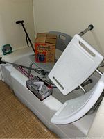 Photo of bathroom with two shower chairs, vaporizer box, travel hair dryer box, adjustable cane, and grabber