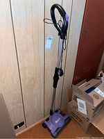 Full view of Shark upright vacuum in purple and black, showing handle, cord, and base.