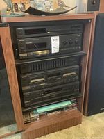 Overall front view of stacked Technics stereo components in wood shelving with manuals and media at base