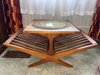 Front angle showing the teak magazine table with slatted rack and rectangular top with stained finish.