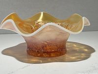 Side view of peach opal carnival glass bowl with six petal design showing embossed floral patterns and ruffled edges.