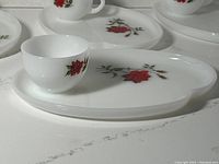 View of white oval snack tray with large red rose print and accompanying matching cup placed on tray.