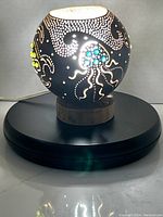 Front view of the lit coconut lamp showing octopus with turquoise stone accents and sea turtle with yellow-green stones.