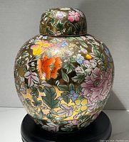Front view of the ginger jar showing colorful floral design on a gold background with lid.