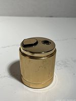 Front angled view of Ronson gold electric lighter showing cylindrical ridged body and top ignition button
