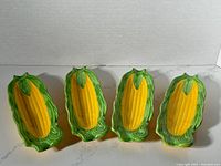 Photo showing front view of the four vintage corn on the cob trays arranged side by side.