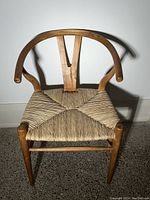 Front view of Wishbone style dining chair showing curved wooden backrest and woven seat.