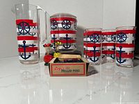 Photo showing the full vintage 1980's Culver acrylic nautical themed drinks set including pitcher, ice bucket, 4 glasses, and cocktail picks.