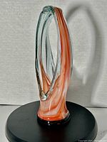 Full front view of the pink and white swirled glass vase showing oval open shape with black base.