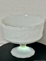 Full view of vintage round footed milk glass compote bowl showing scalloped edge and detailed floral pattern on the body.