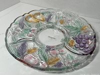 Full top view of the round colored glass serving tray showing fruit and leaf designs with four compartments.