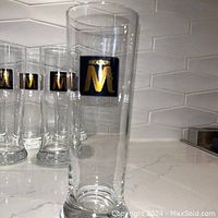 Photo showing a close-up of one vintage Molson pilsner glass with the black and gold emblem clearly visible, other glasses in the set visible in the background.