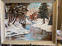 Framed oil painting showing winter landscape with snow, creek, trees, and red watermill.
