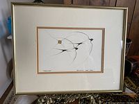 Full view of framed and matted artwork "Swallows" showing three swallows flying, done in ink with brown accent, in a simple gold-tone frame.