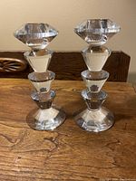 Pair of vintage glass crystal candle holders on wooden table, front-facing view showing detailed faceted crystal design.