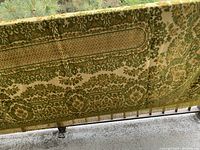 Full view of the velvet throw cloth hanging over railing showing green and gold pattern with fringe