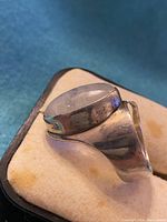 Close-up view of the silver ring with moonstone from an angled side perspective on a beige jewelry pad.