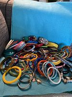 Wide view of the collection showing the variety of colorful plastic, metal, and beaded bangles and bracelets