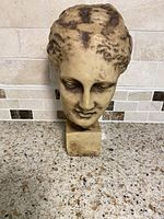 Frontal photo of the Greek goddess head bust showing detailed facial features and hair styling with aged finish.