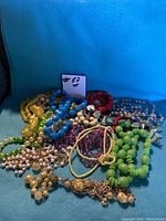 Overhead view of multiple vintage style necklaces in a heap showing color variety and bead types