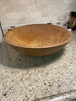 Large vintage wooden bowl shown from top angle on countertop, displaying the interior and rim.