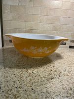 Side profile showing the yellow exterior with white floral design and pouring spout.