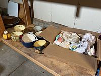 Entire lot of ceramic bowls, mugs in cardboard box and teapot on wooden shelf