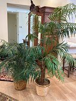 Photo showing two faux palm plants placed side by side, highlighting their height difference and leafy green fronds.