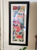 Full view of framed floral wall art print hung on a wall, showing artwork and frame.