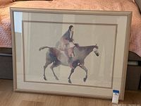 Full view of the framed art print showing the Native American figure on horseback, glass covered and matted in a frame.