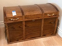Full front and top view of oak dome top blanket chest showing natural finish and side handles.