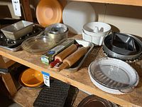 Shelf with a variety of kitchen bakeware including pans and rolling pins.