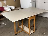Full view of the work table opened with MDF top in white and wooden frame with casters